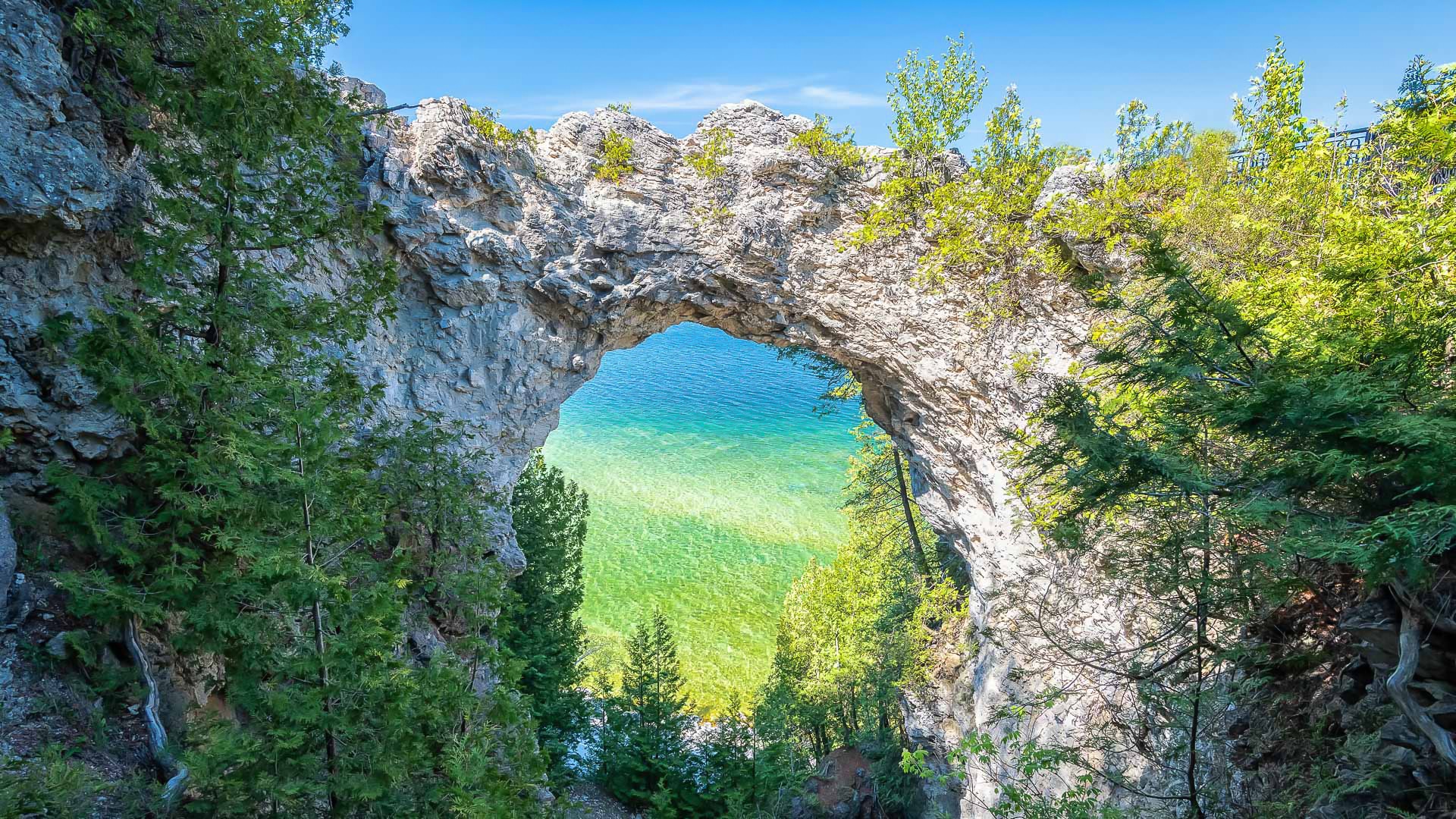 a rock arch with trees and water in the background