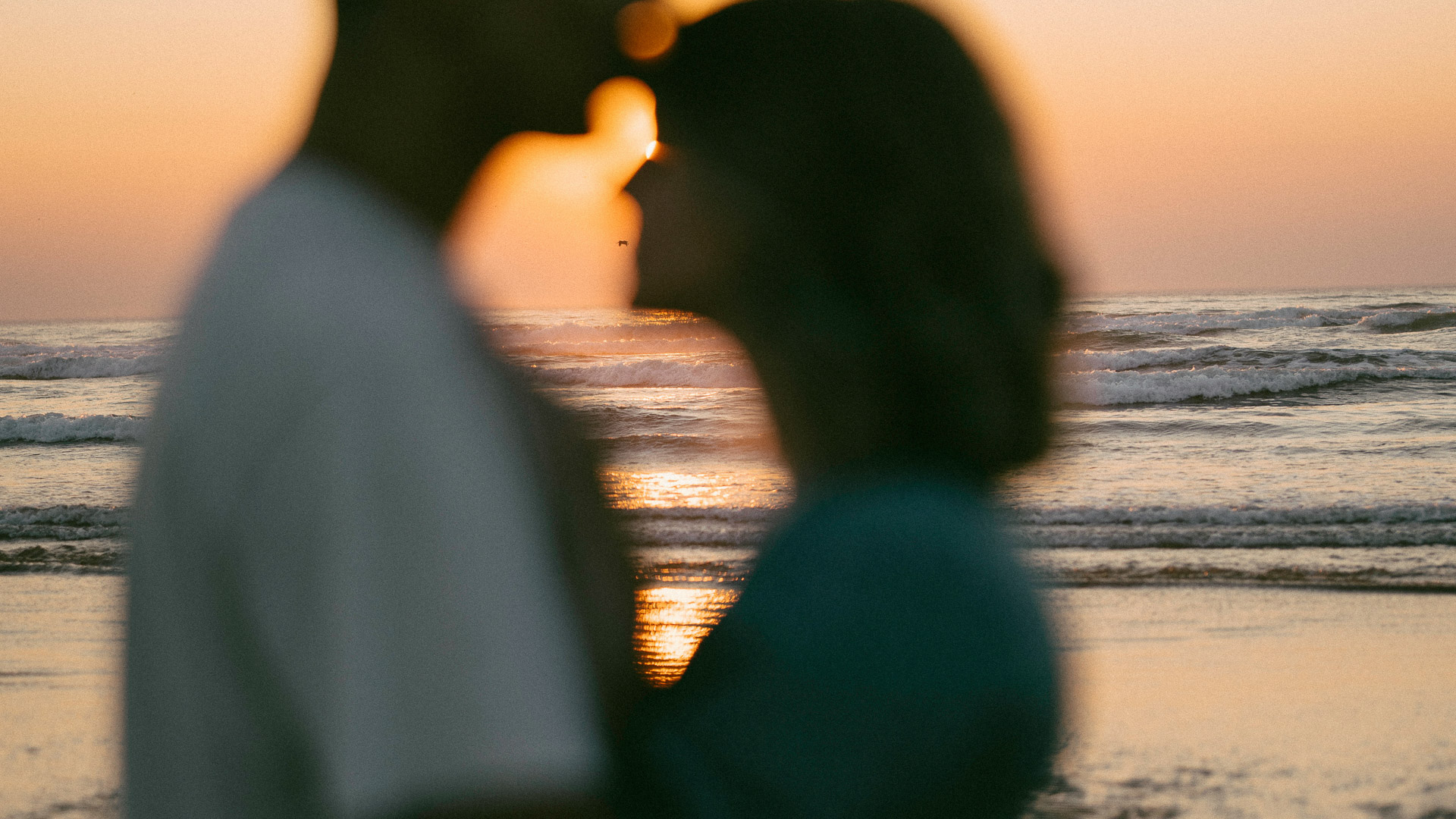 a silhouette of a man and woman kissing at the beach
