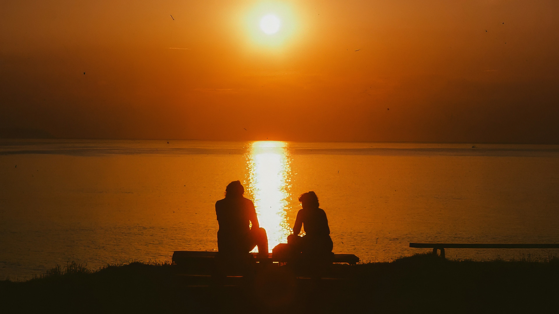 a group of people sitting on a bench by the water