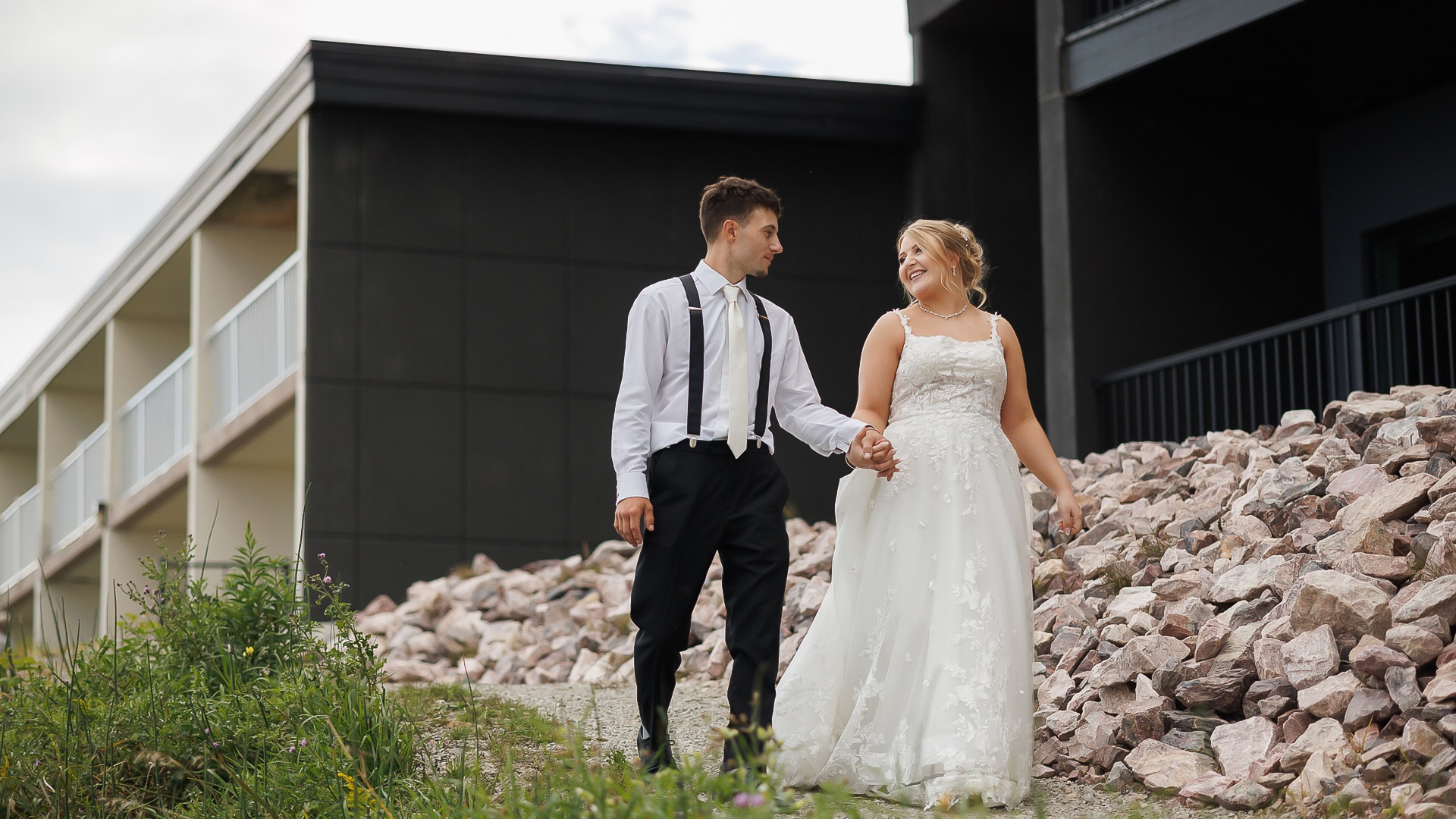a man and woman holding hands and walking on a rocky hill