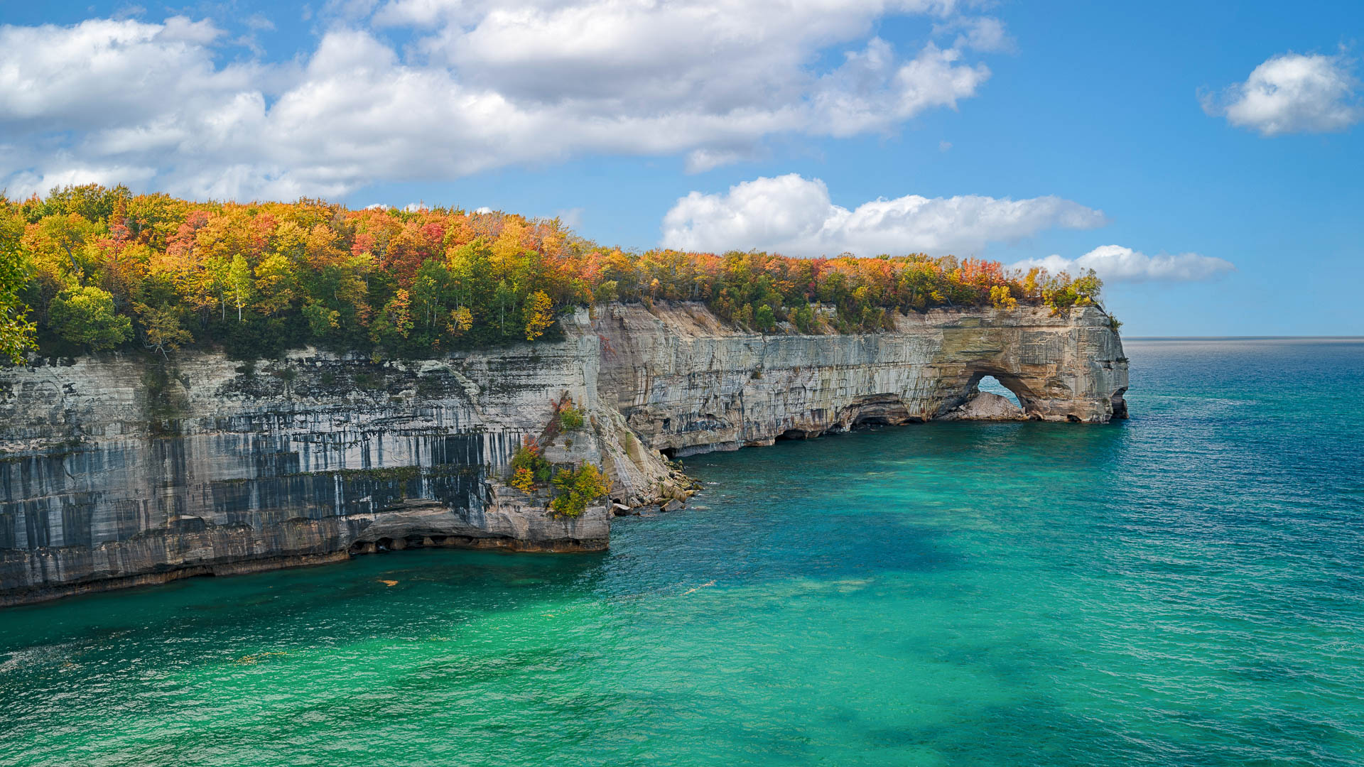 a cliff with trees on it with Pictured Rocks National Lakeshore in the background