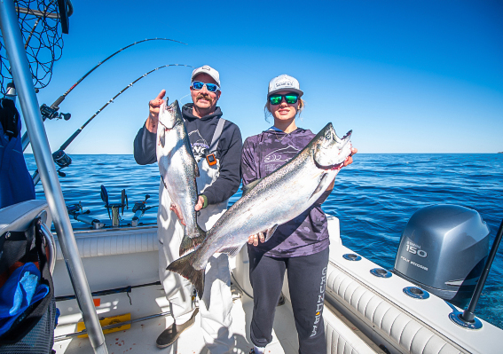a man and woman holding fish on a boat