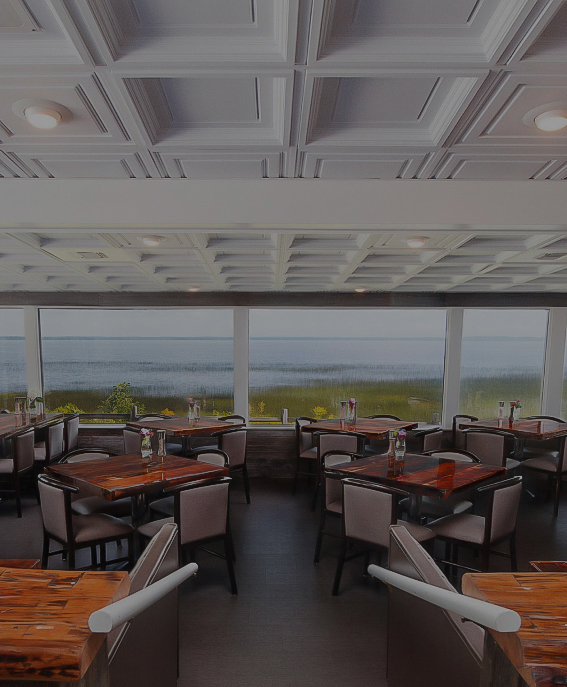 a room with tables and chairs and a view of the ocean