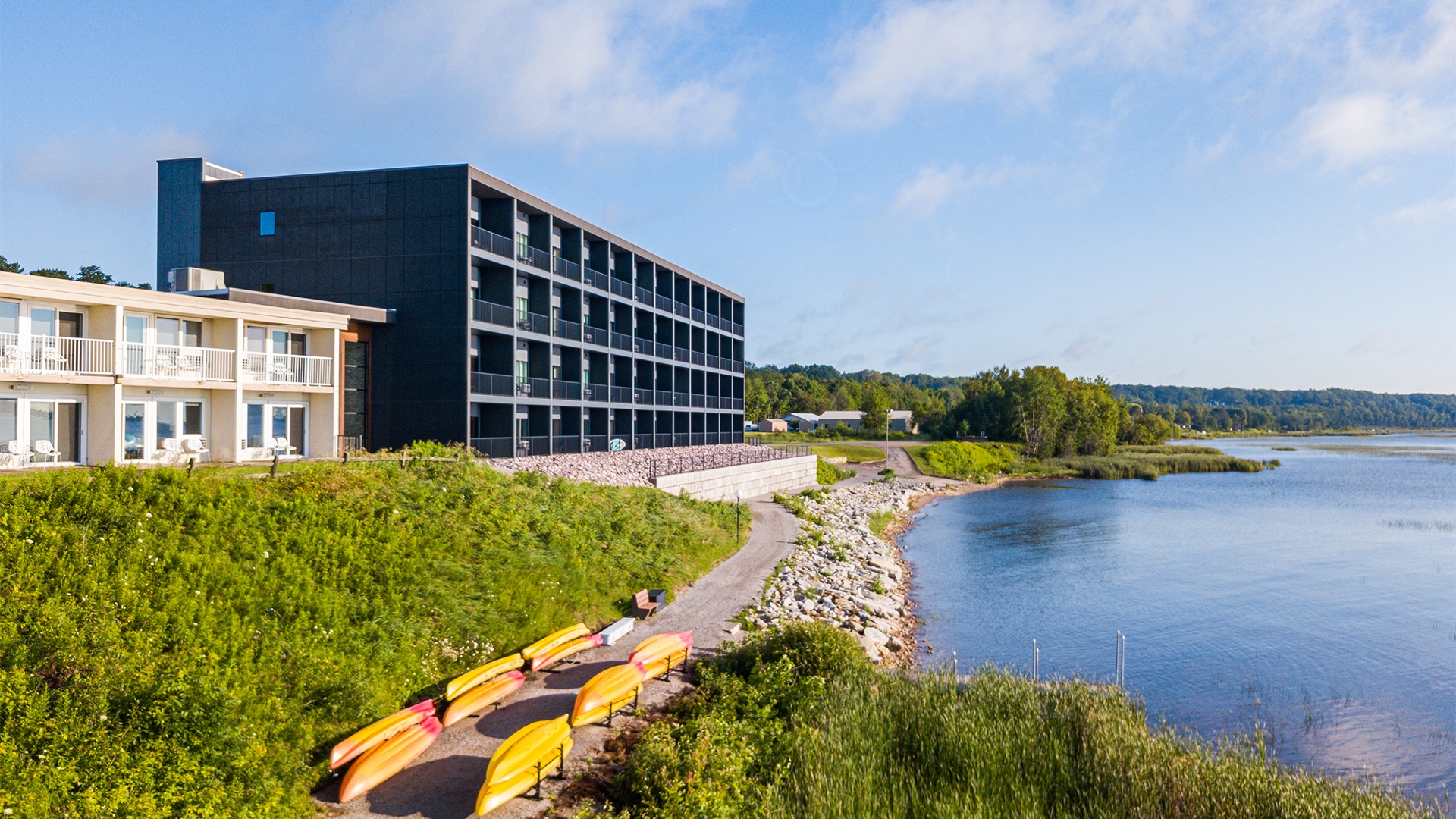 a building with a body of water and a row of yellow canoes