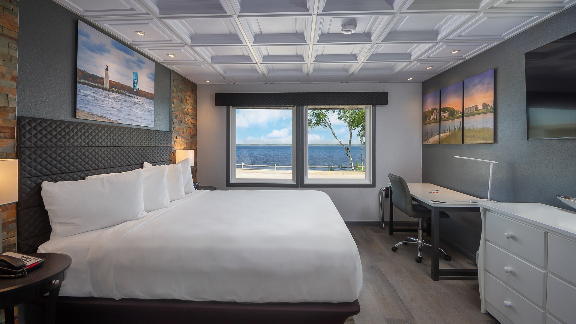 a room with a large bed and a desk and a large window