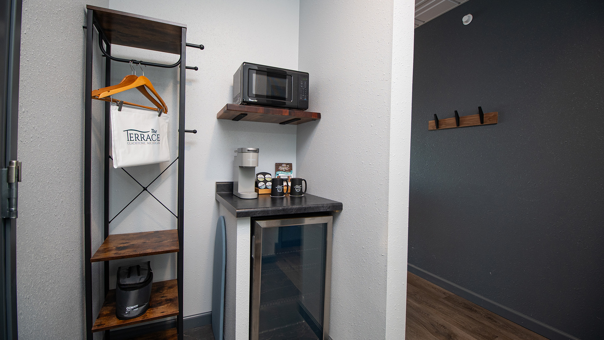 Hotel room amenity station with a mini-fridge, coffee maker, microwave, and open wardrobe