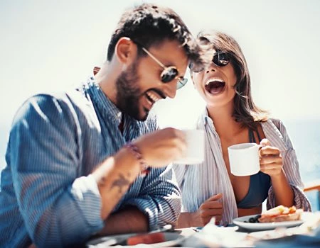 man and woman drinking coffee outside laughing