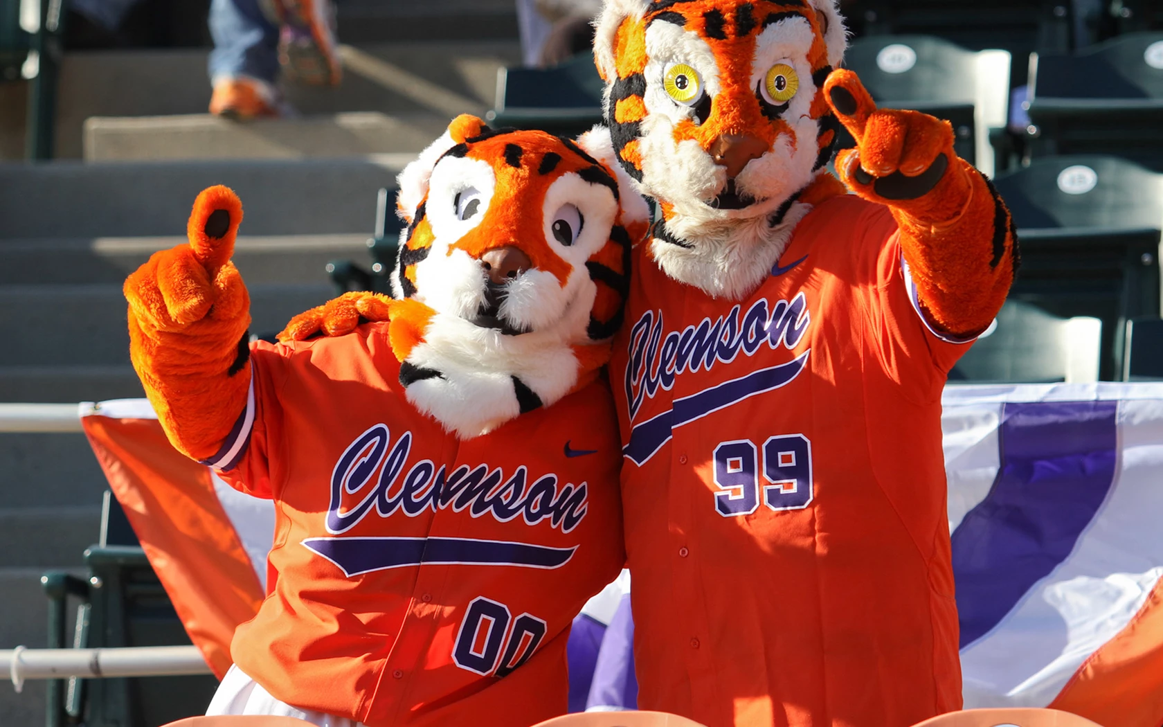 two tiger mascots standing with a finger 