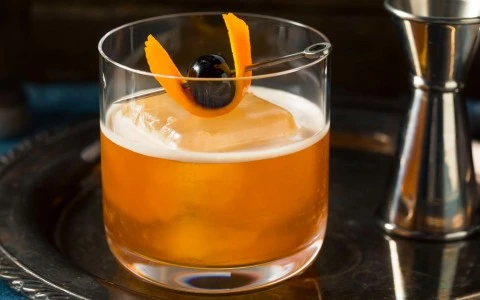 a glass of liquid with fruit and a cherry on top