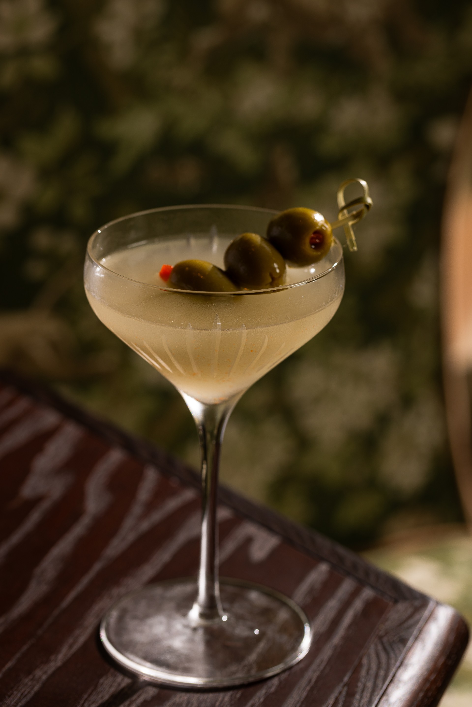 a glass with a drink and olives on it