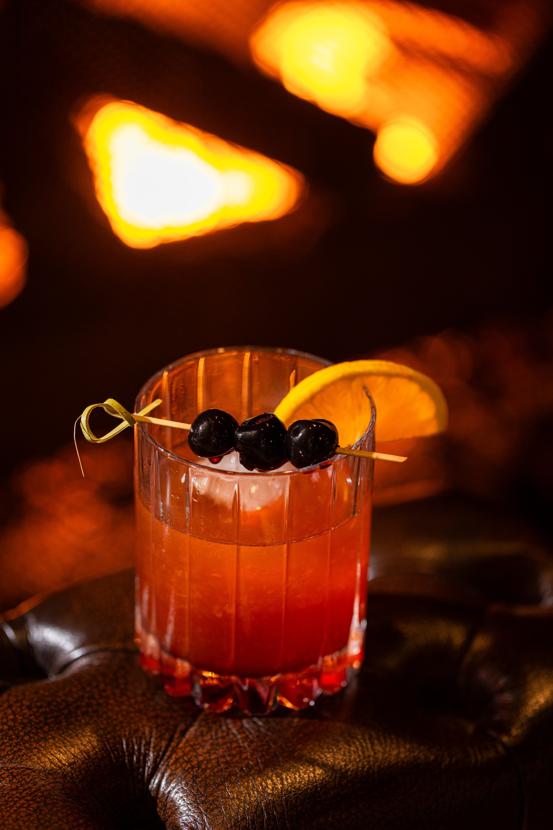 a drink with orange liquid and black berries