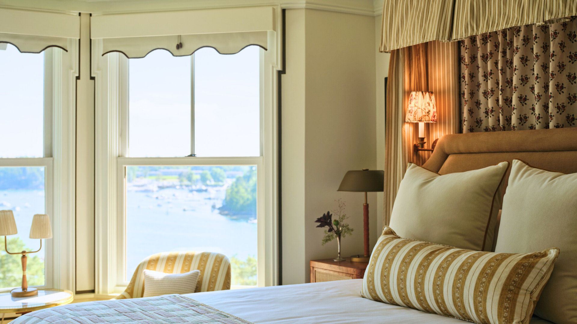 a bed with pillows and a window overlooking a body of water