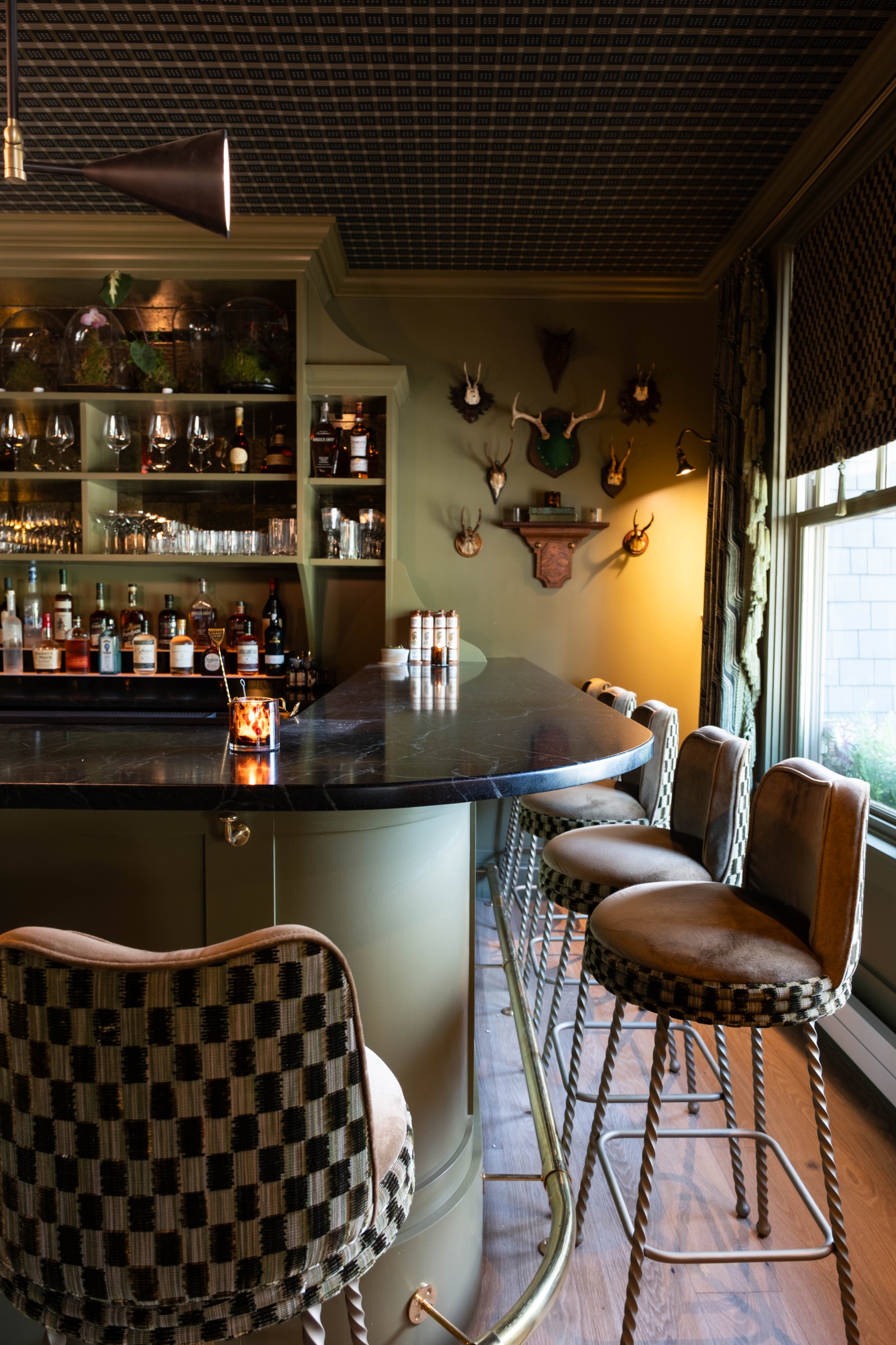 a bar with chairs and a shelf with liquor bottles on the wall