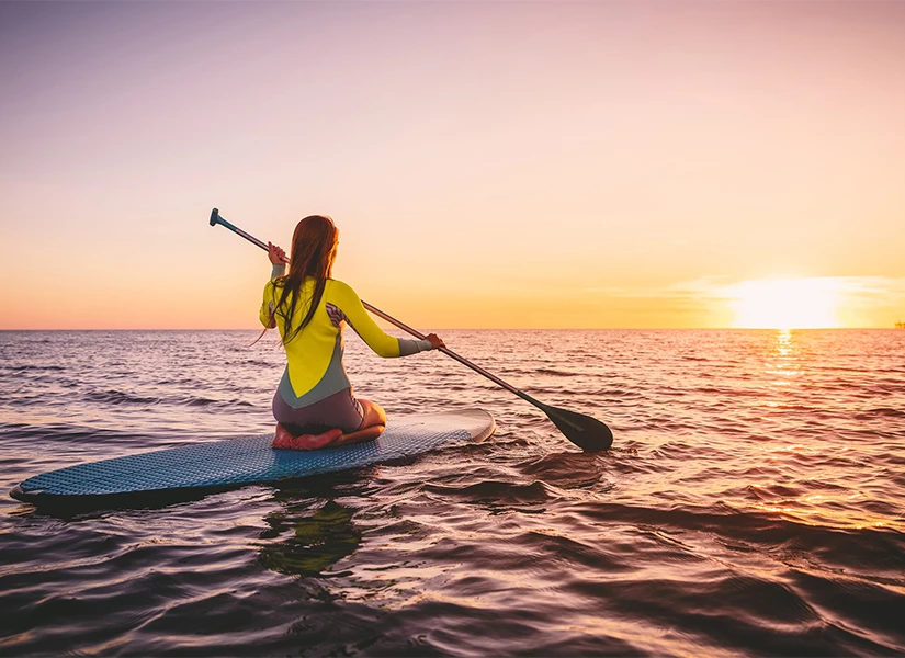 a woman on a surfboard with a paddle in the water
