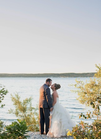 a man and woman kissing on a dock near water