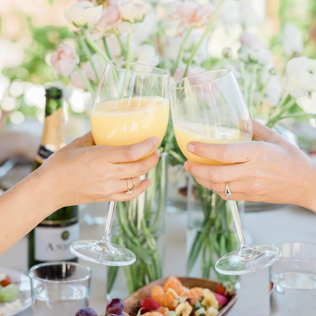 a pair of hands holding wine glasses