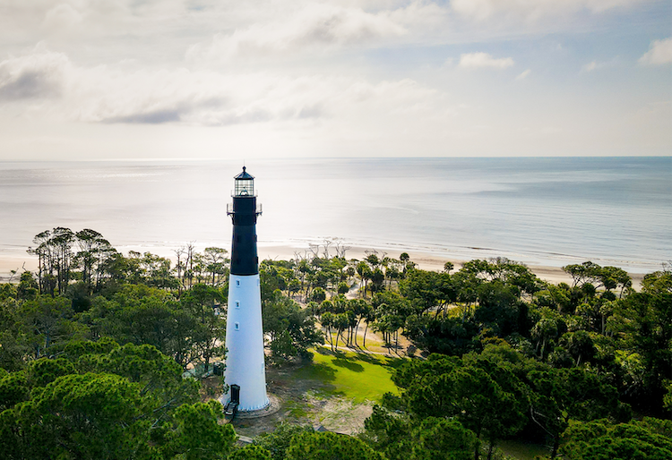 a lighthouse with trees and water in the background