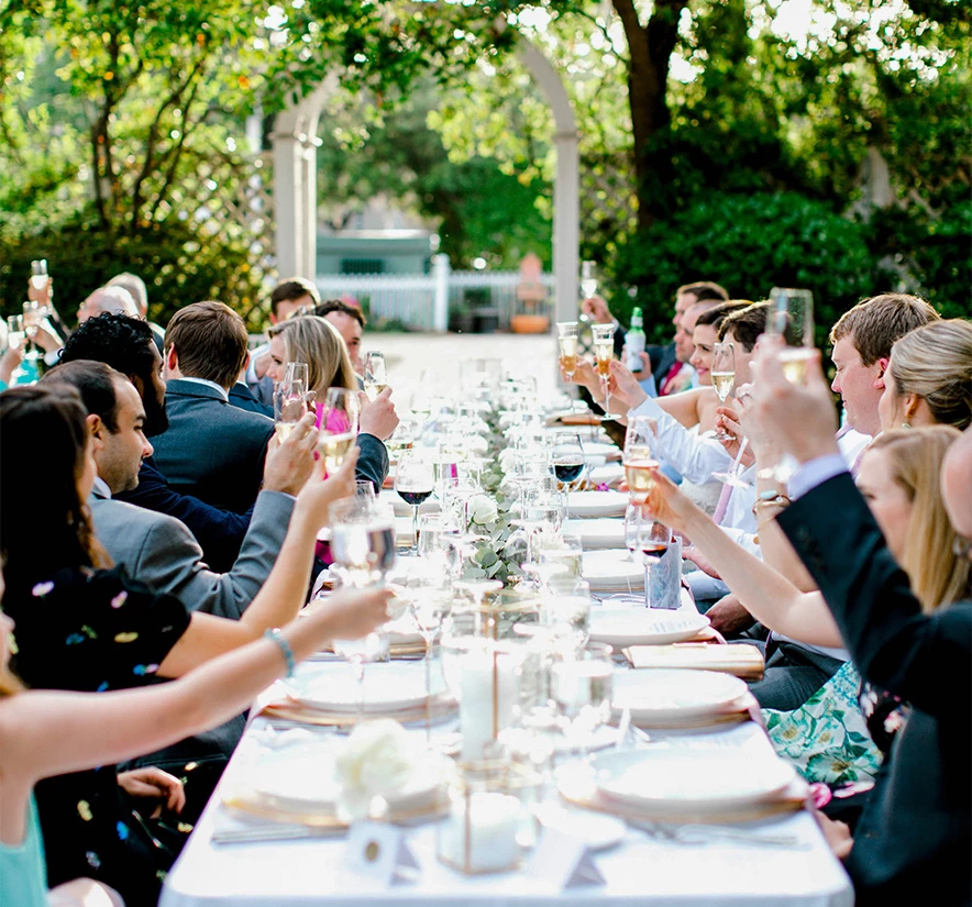 a group of people sitting at a long table with glasses of wine