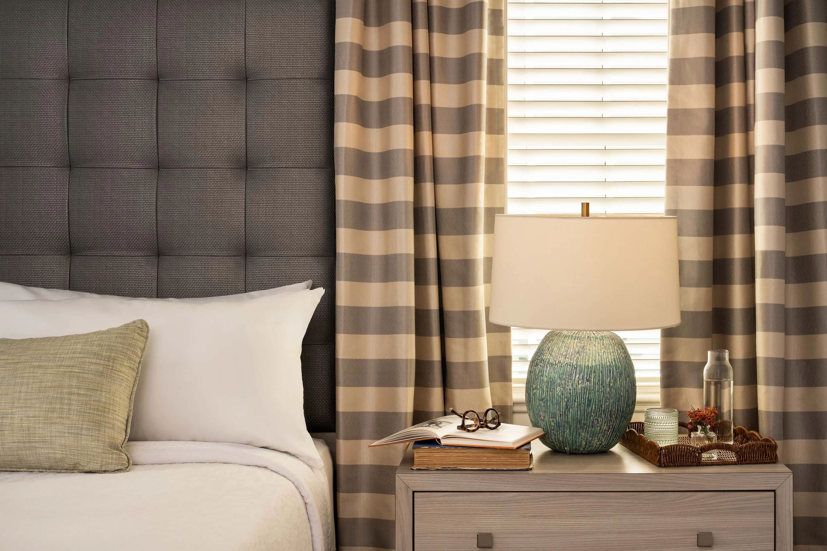 a lamp on a nightstand next to a bed