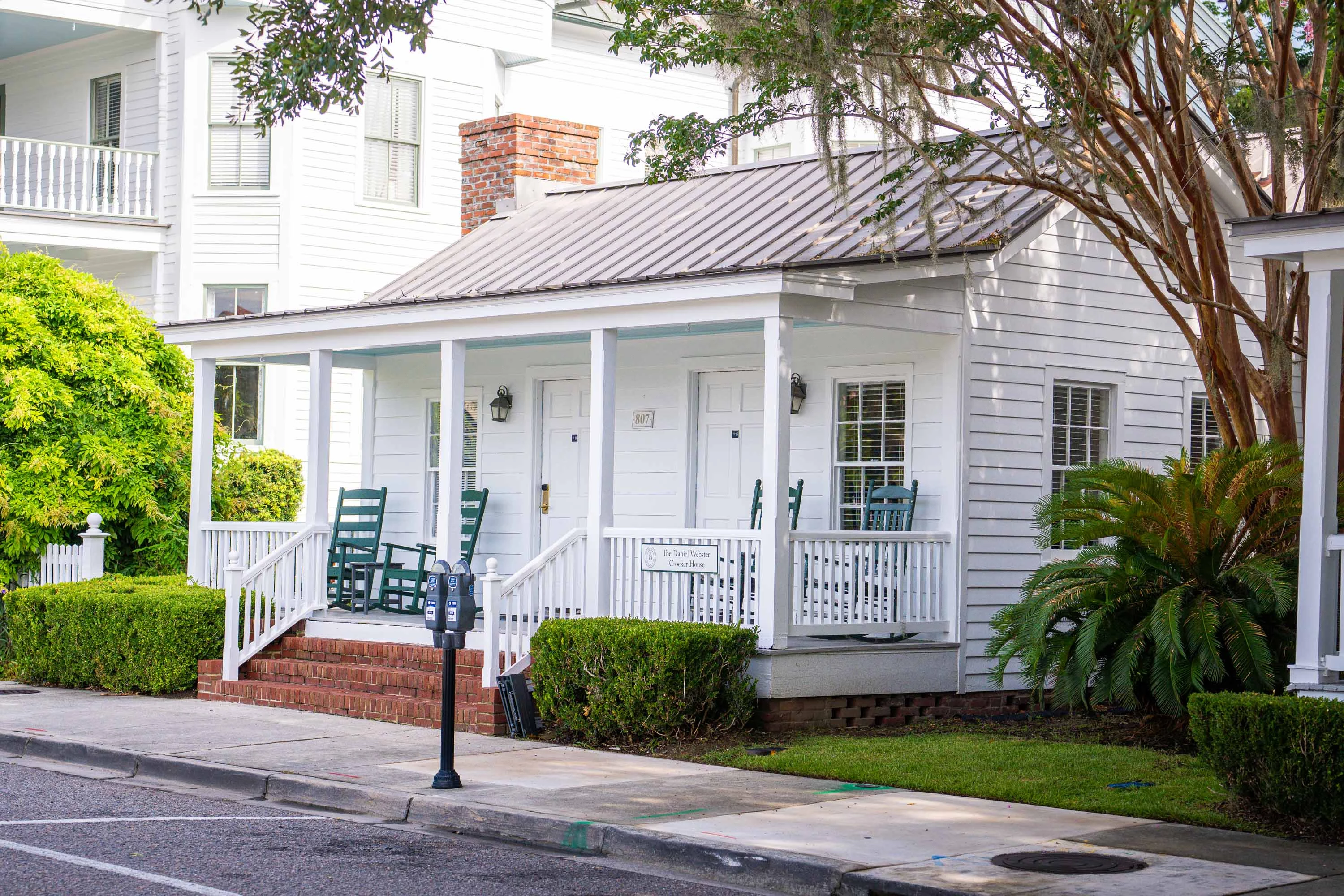 a white house with a porch and a tree