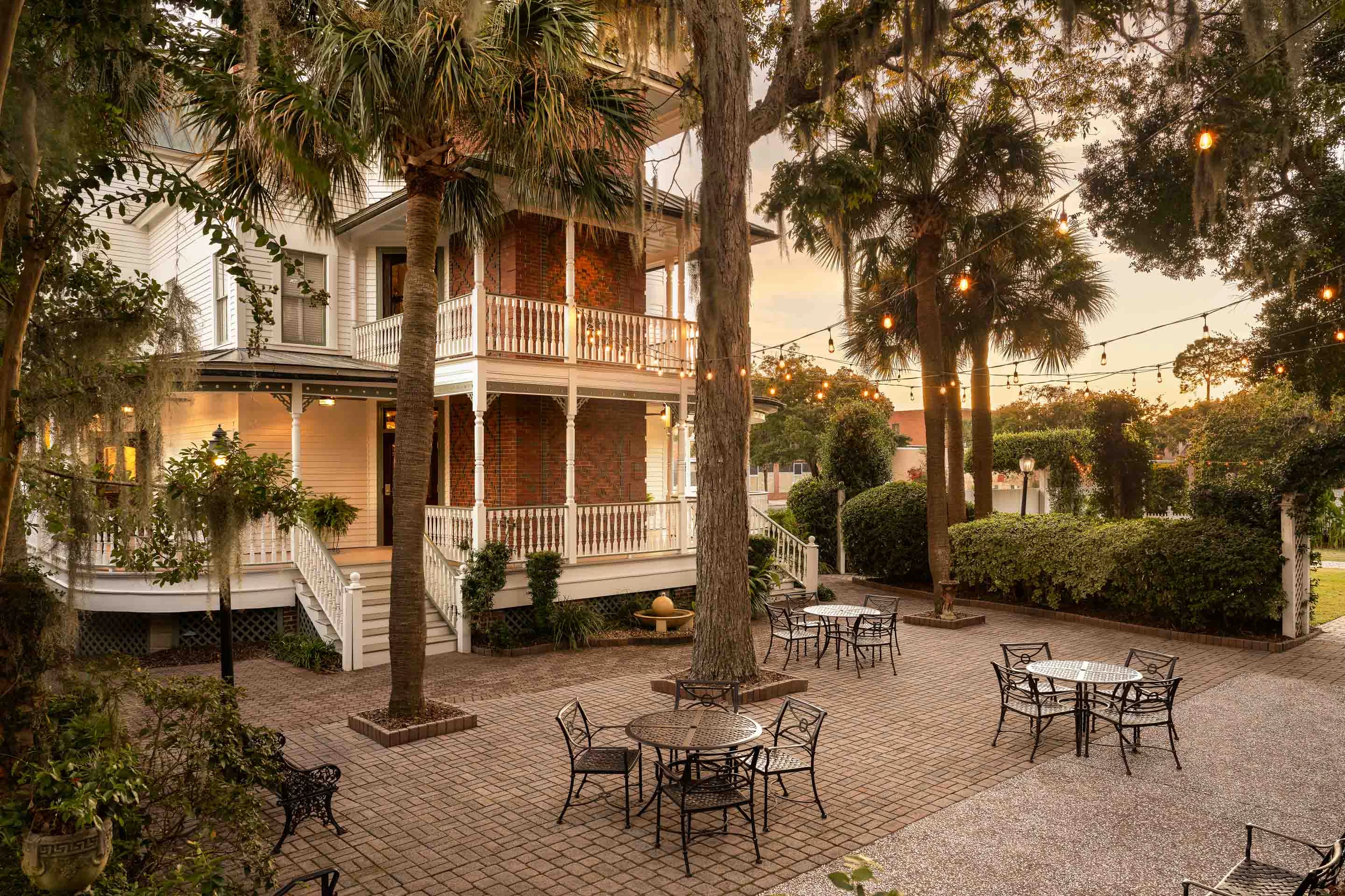 a patio with tables and chairs in front of a house