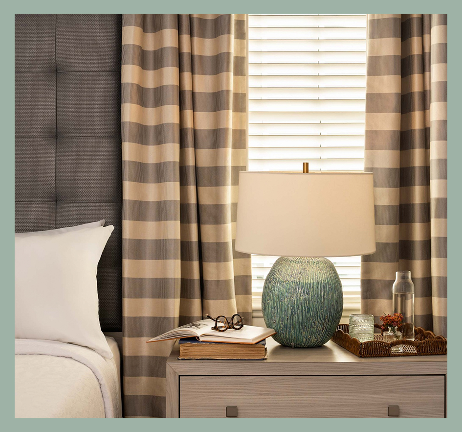 a lamp on a table next to a bed