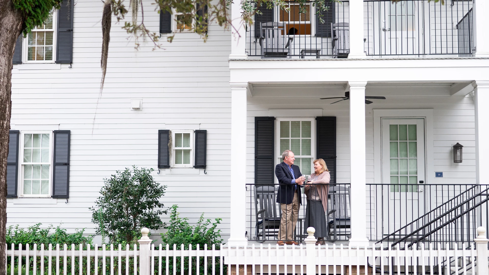 a man and woman standing on a porch of a house