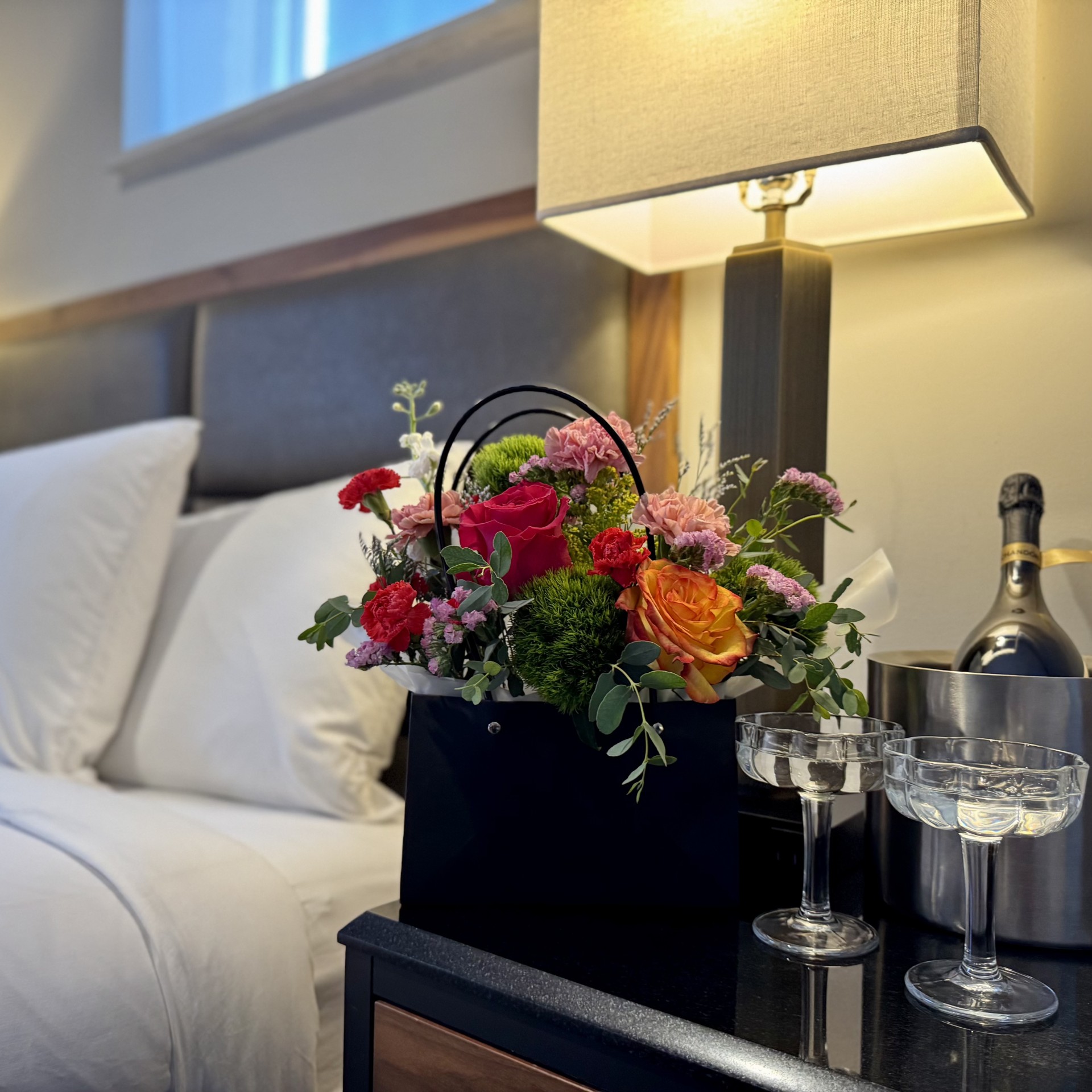 a bouquet of flowers in a basket on a table next to a bed