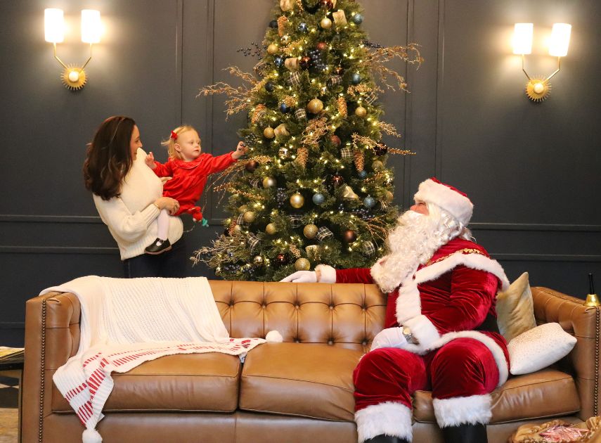 a man in santa garment and a woman in front of a christmas tree