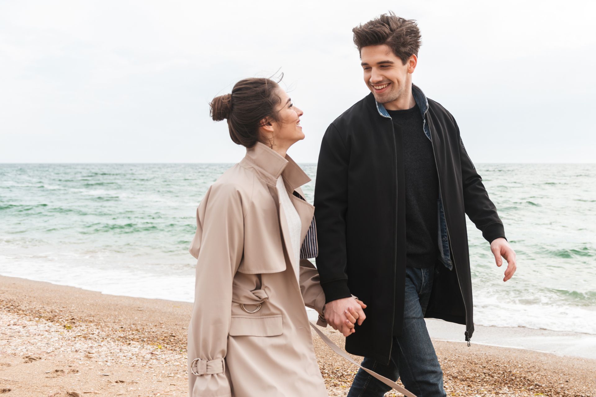 a man and woman holding hands on a beach
