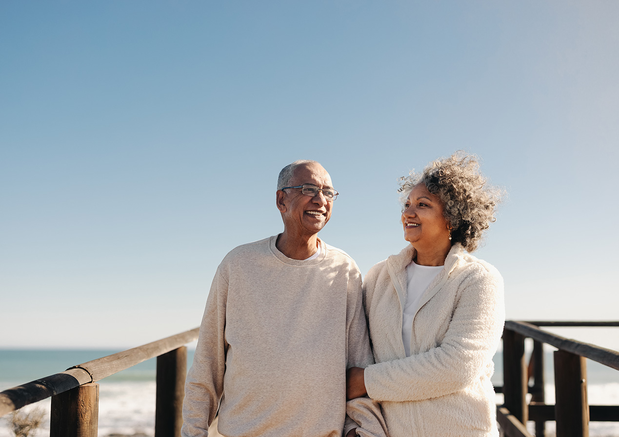 a man and woman standing on a boardwalk on the beach