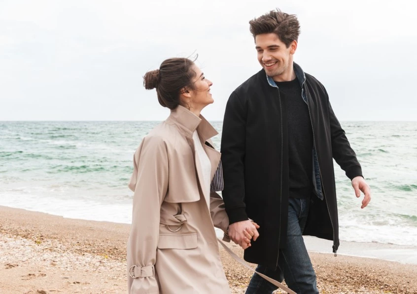a man and woman holding hands on a beach
