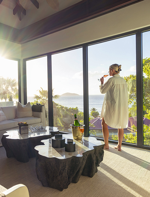 a woman in a white robe drinking from a straw in front of a large window
