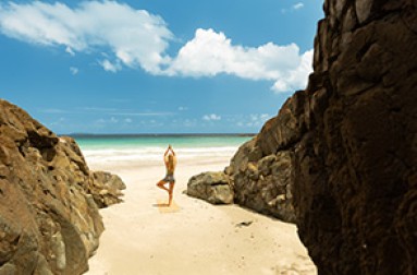 a woman standing on a beach with rocks and water in the background