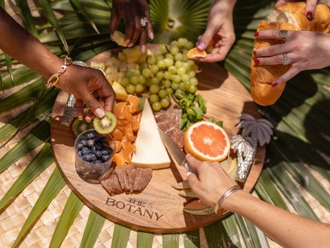 a group of people cutting fruit on a wooden board