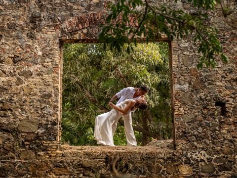 a man and woman in white clothes kissing in a stone frame