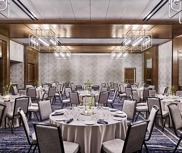 meeting space set up for an event with glassware and flowers on the table