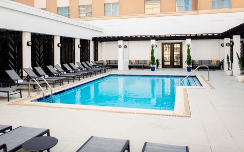 a pool with lounge chairs and a building