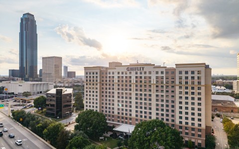 a large building with many windows and a road with trees and a city in the background