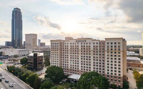 a large building with many windows and a road with trees and a city in the background