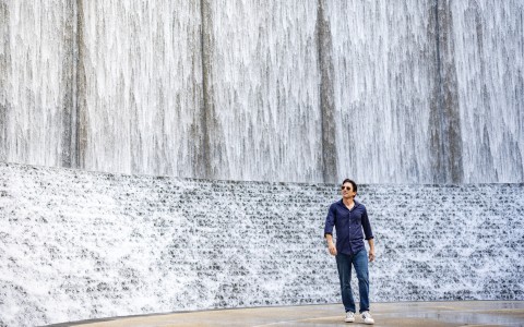 a man standing in front of a waterfall