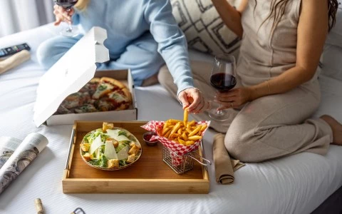 a couple of people sitting on a bed eating food