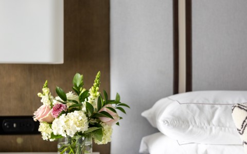 a vase of flowers on a table next to a bed