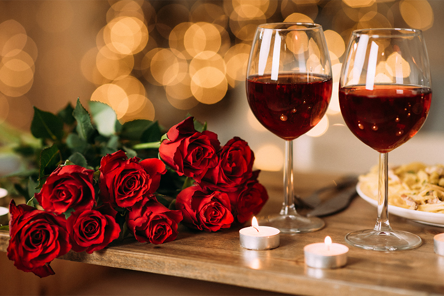 a couple of wine glasses and roses on a table