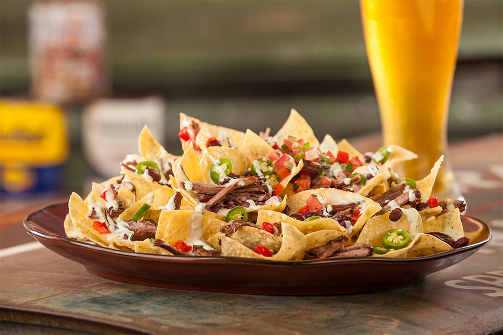 a plate of nachos with meat and jalapenos