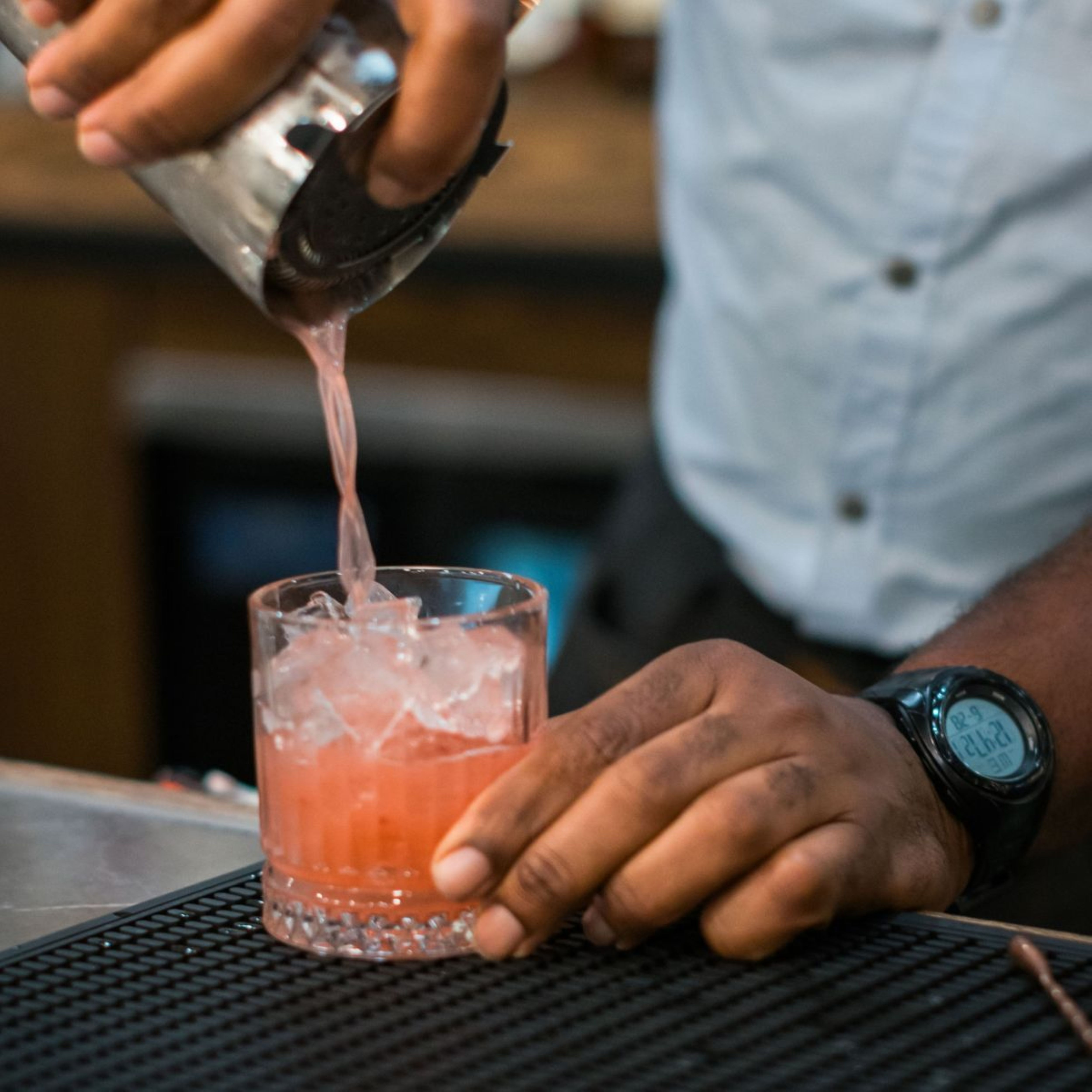 a cocktail glass with lemons and a shaker on a bar counter