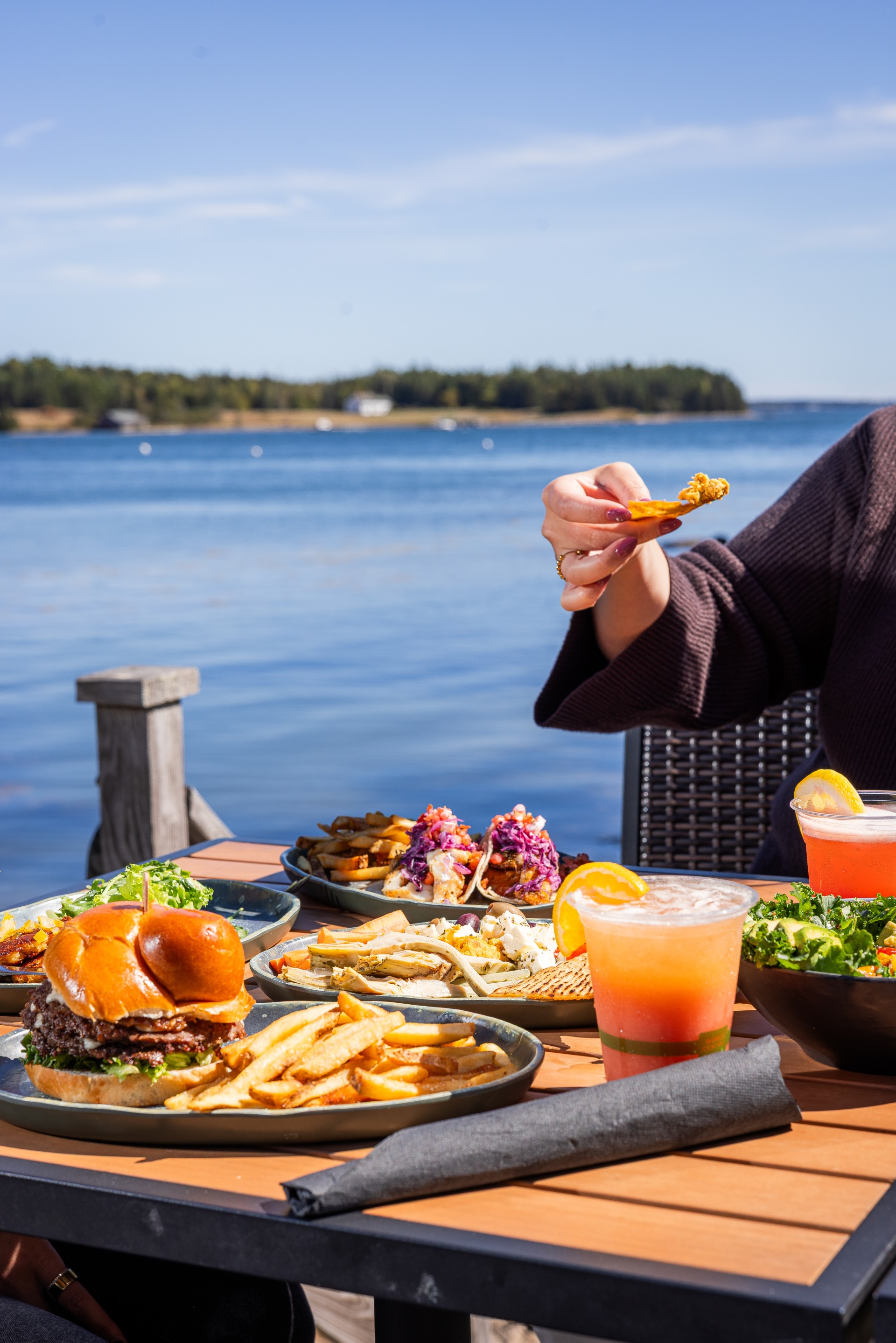 a person eating food on a table with water in the background