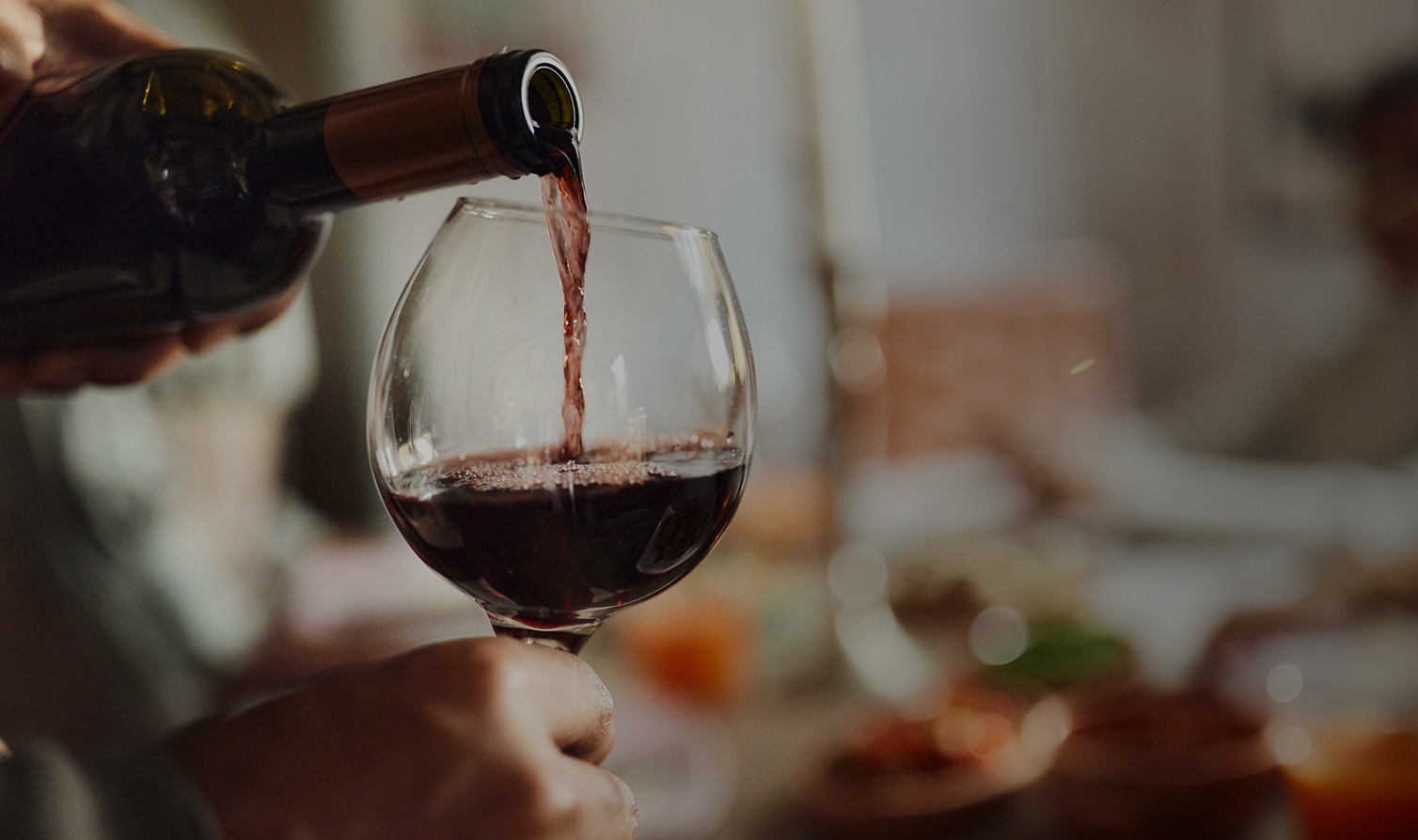 a person pouring wine into a glass