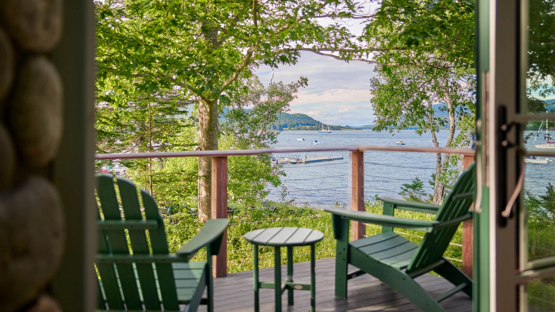 a deck with chairs and a table overlooking a body of water