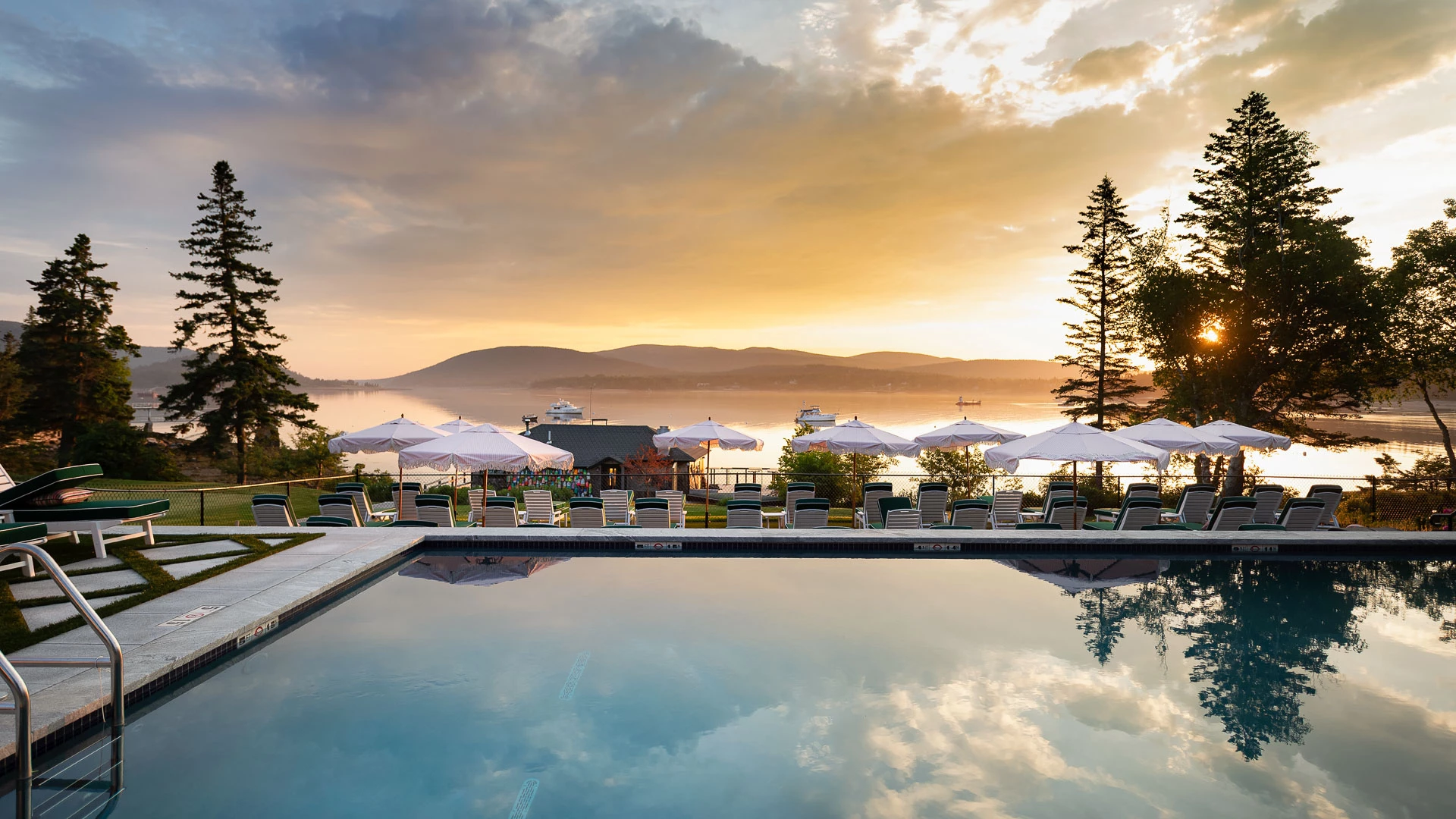 a pool with umbrellas and chairs by a body of water
